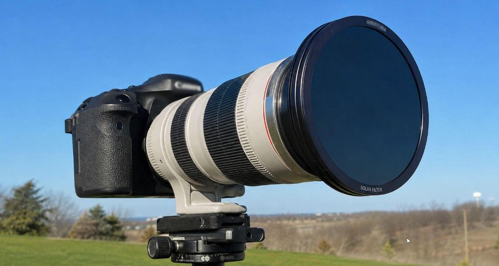 DSLR camera with a telephoto lens and a front-mounted solar filter labelled for safe solar photography on a tripod.