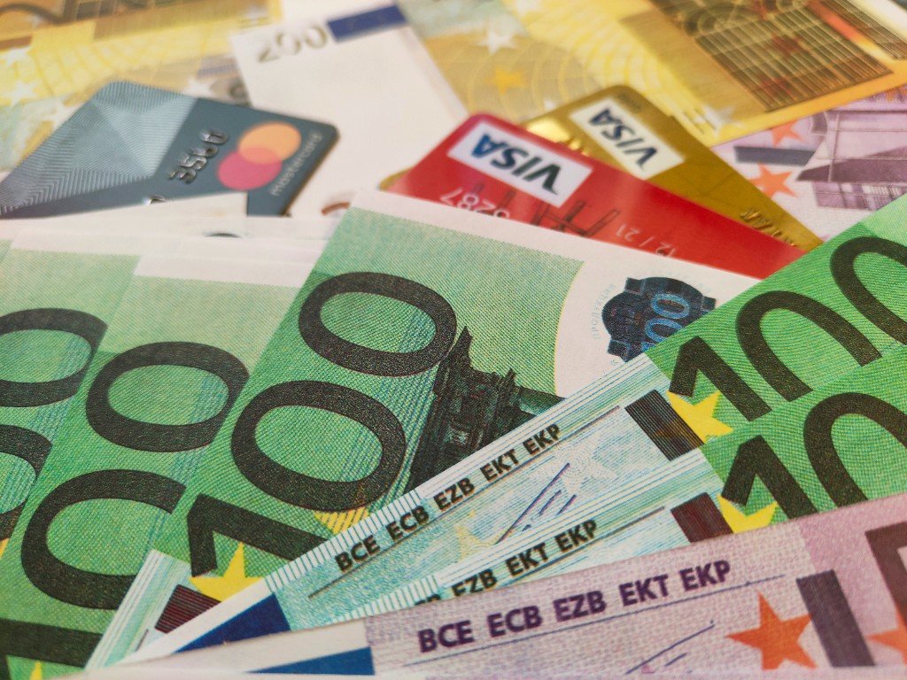 Euro banknotes and Visa and Mastercard payment cards piled together — the cash and cards travellers carry on eclipse trips.